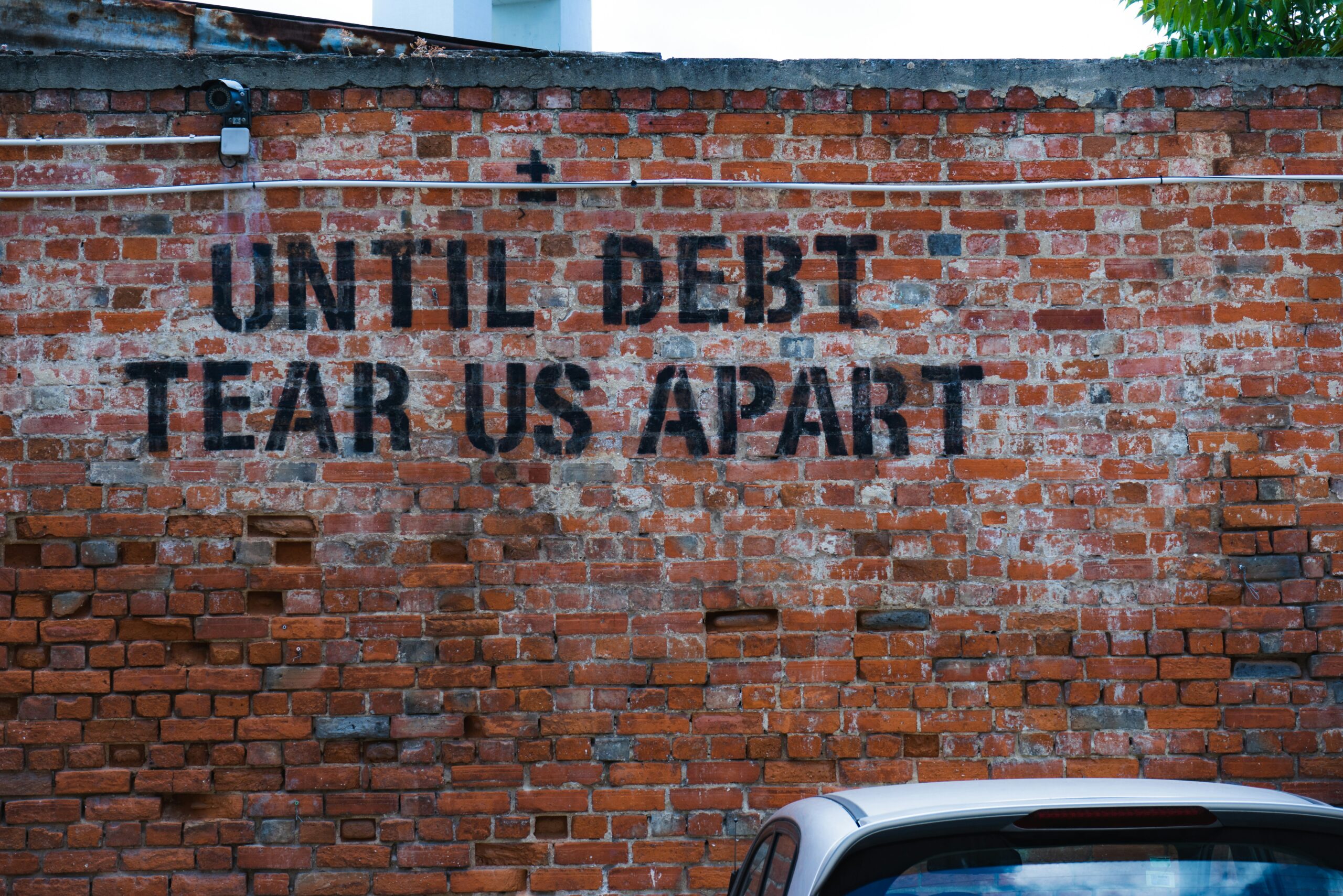 Brick wall with "Until Debt Tear Us Apart". how to pay off credit card debt fast