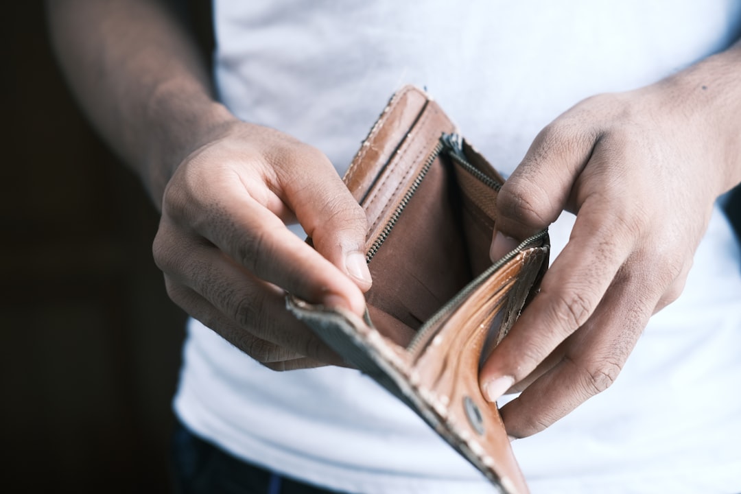 Person reviewing bills and budget papers with calculator on desk, working on debt reduction plan