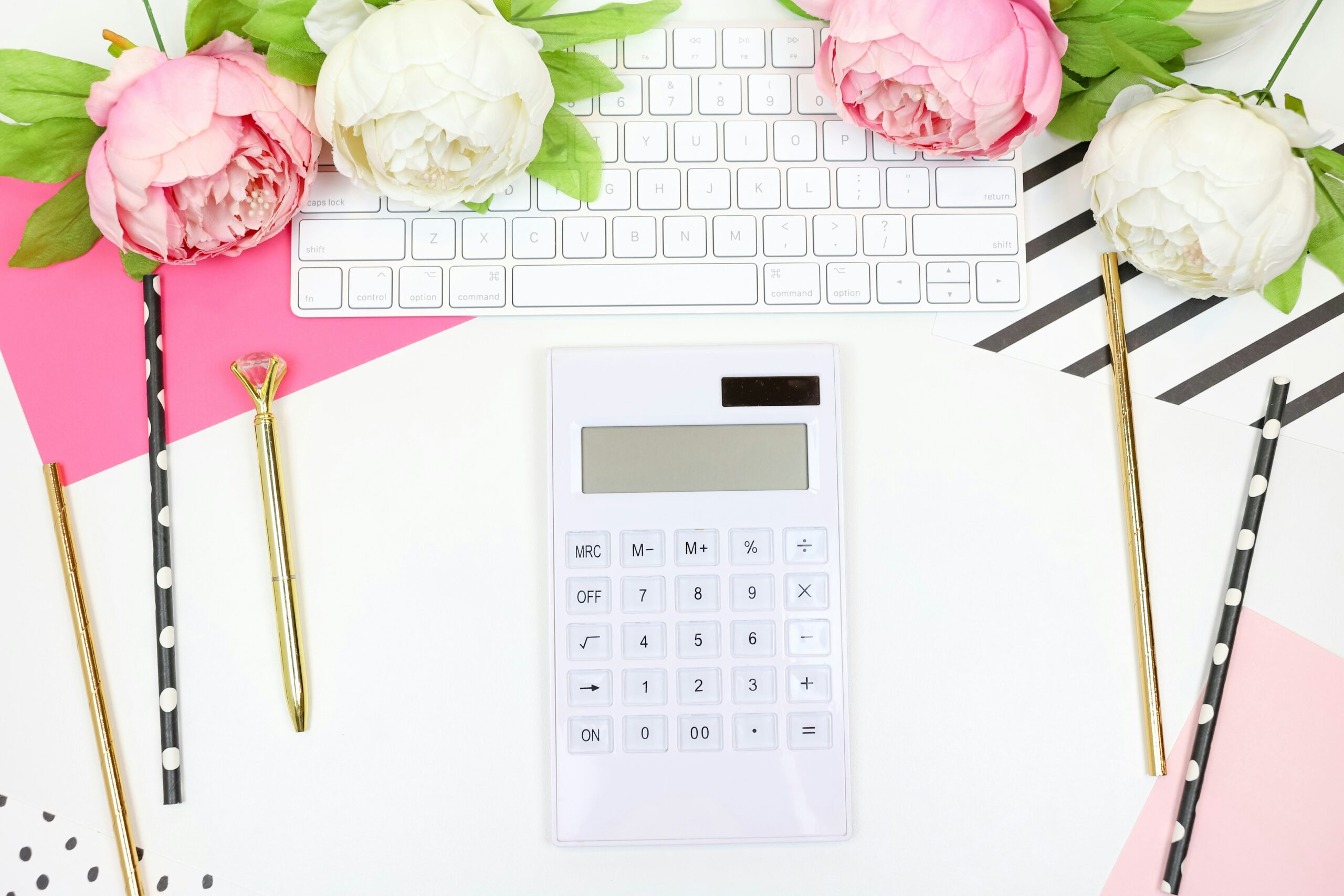 Calculator with flowers and keyboard on pink desk. how to create a monthly budget step by step