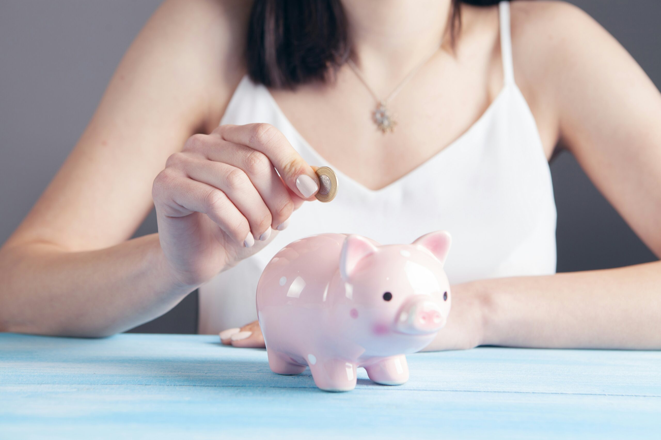 what is a high yield savings account. Image of a woman saving money, putting coins in a piggy bank