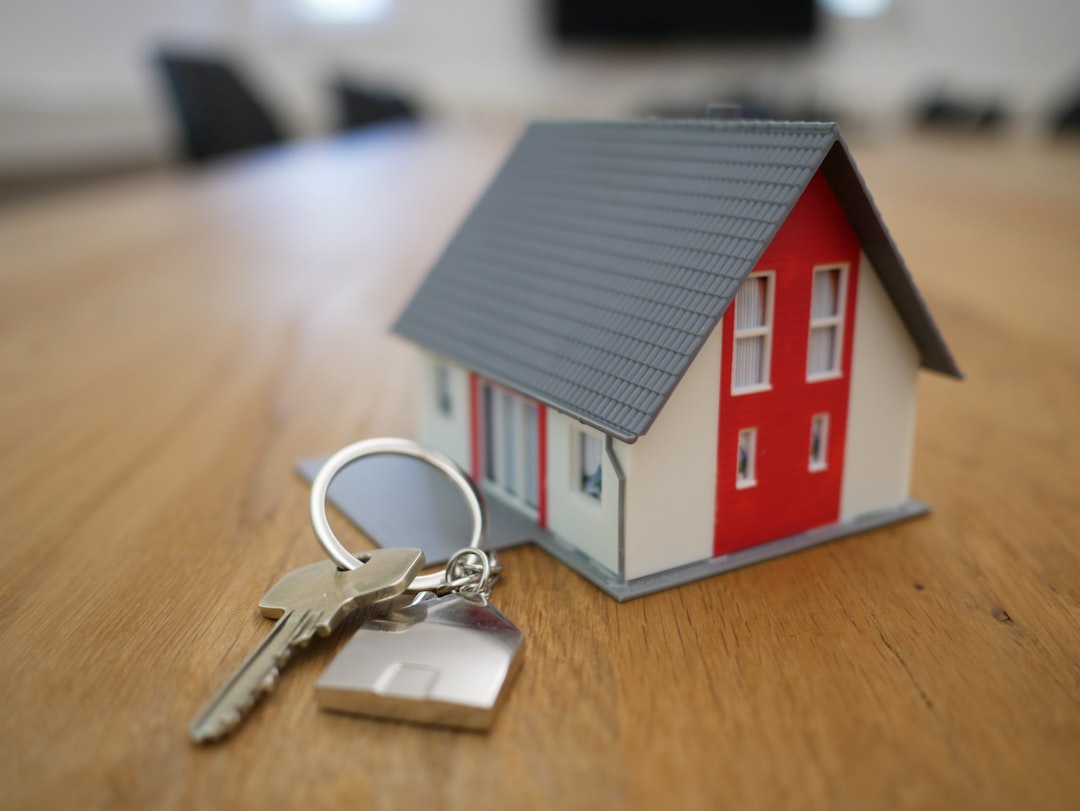 Miniature house model resting on stacked coins beside upward-trending investment graph