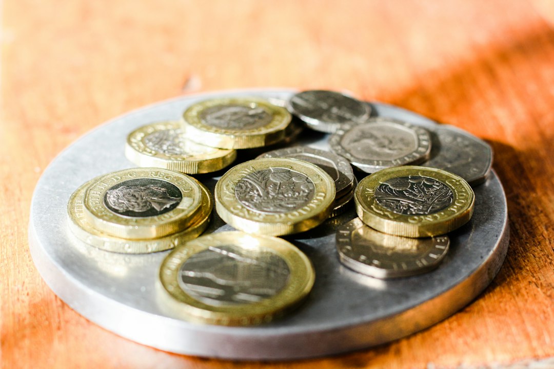 UK coins and banknotes stacked beside a house model, symbolizing passive income sources
